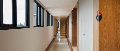 A long, narrow hallway with large windows on one side and wooden paneling on the other.