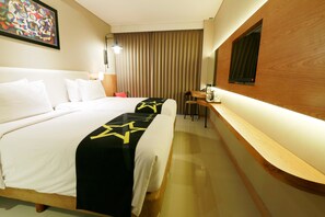 A hotel room with a large bed, a desk, and a mirror. - Yellow Star Hotel Gejayan (Depok)