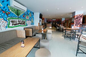 A modern restaurant interior with a mural, seating arrangements, and a counter.