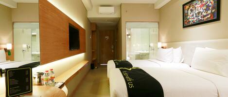 A hotel room with a bed, a desk with a computer, a mirror, and a painting on the wall.