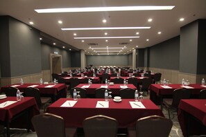 A conference room with multiple tables, chairs, and water bottles.