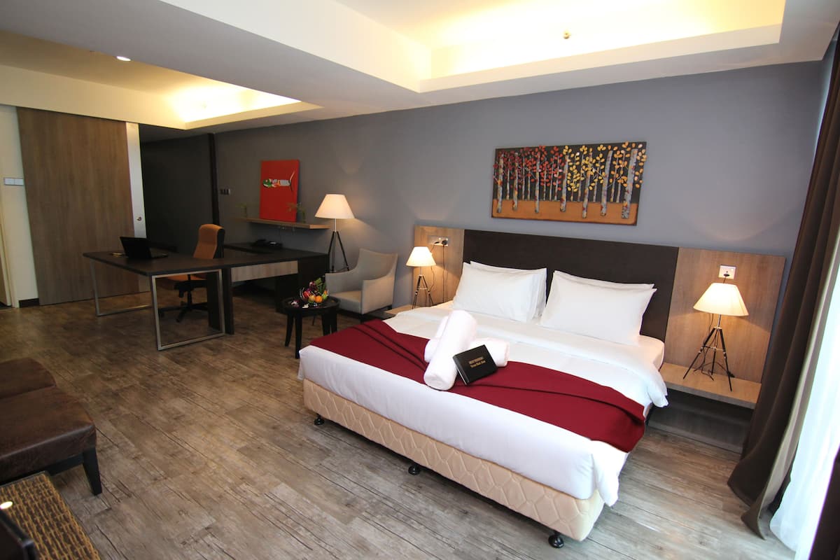 Una habitación de hotel con cama, escritorio, silla y dos lámparas.