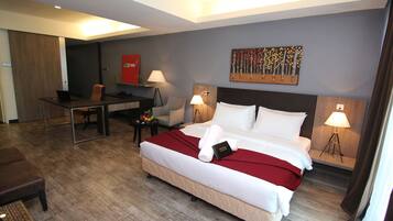 A hotel room with a bed, desk, chair, and two lamps.