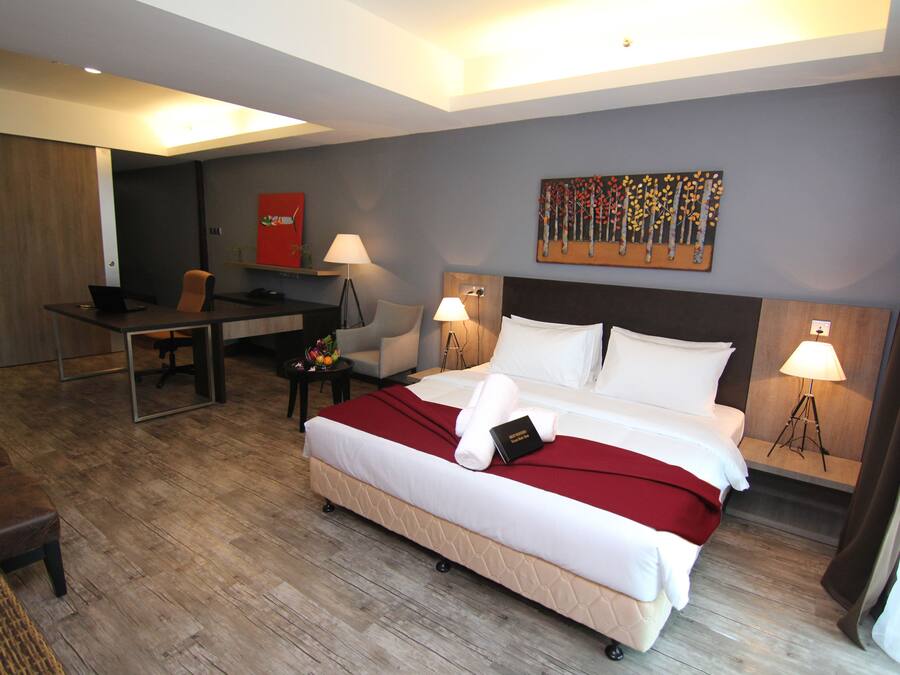 A hotel room with a bed, desk, chair, and two lamps.