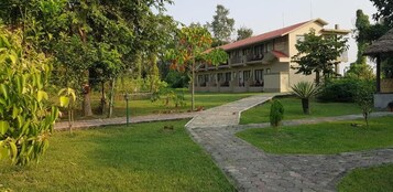 Un hotel con un patio empedrado, un camino que lleva al edificio y un césped bien cuidado.