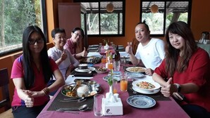 Un grupo de personas comiendo en una mesa con varios platos, una botella de zumo de naranja y un salero.