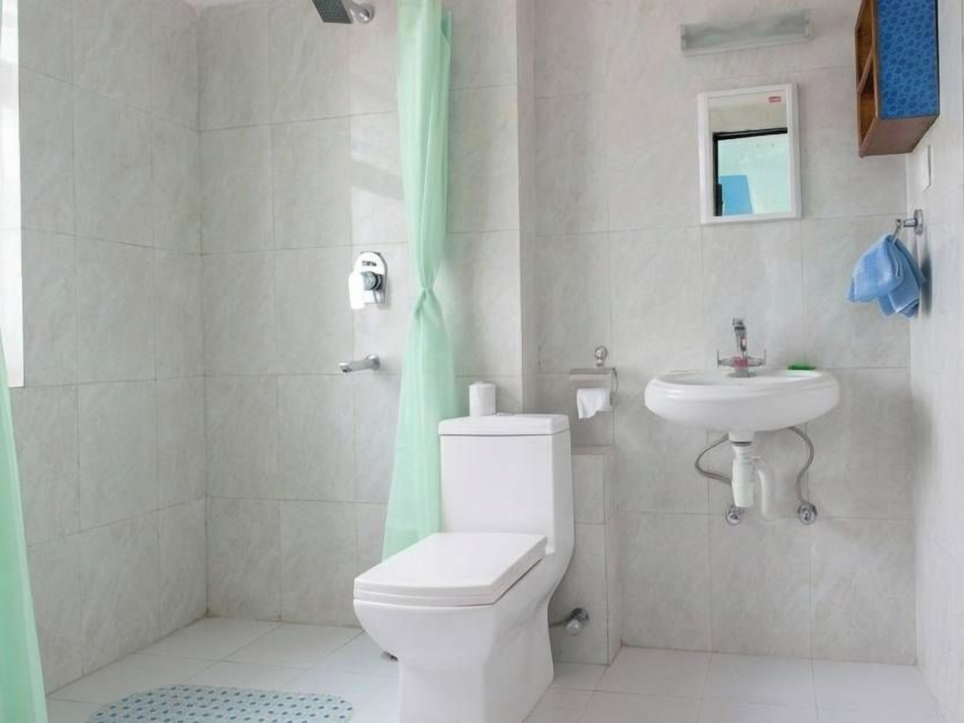A bathroom with a shower, toilet, sink, and a small window.