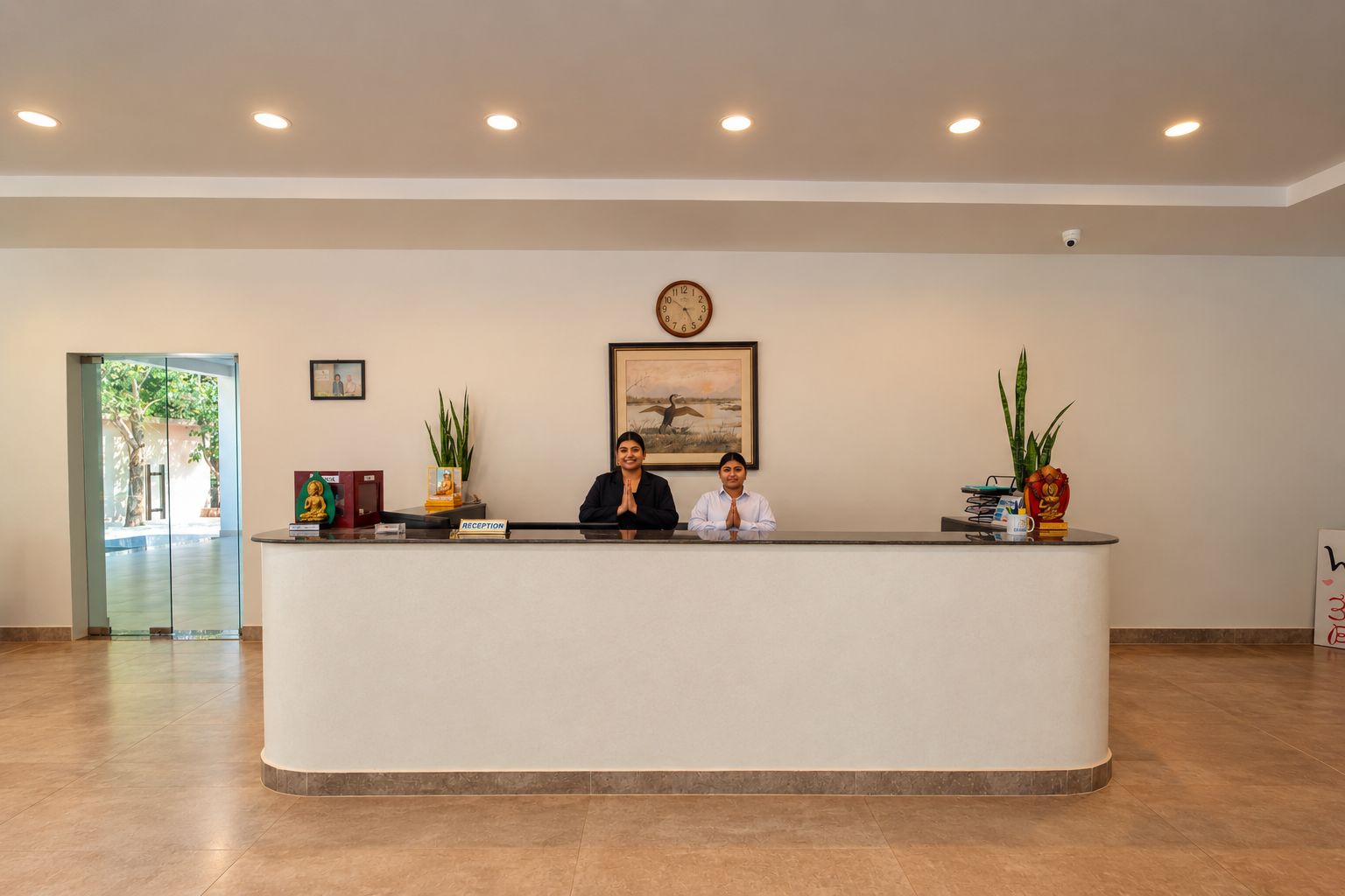 Una mesa de recepción con dos empleados, un reloj y obras de arte enmarcadas en la pared.