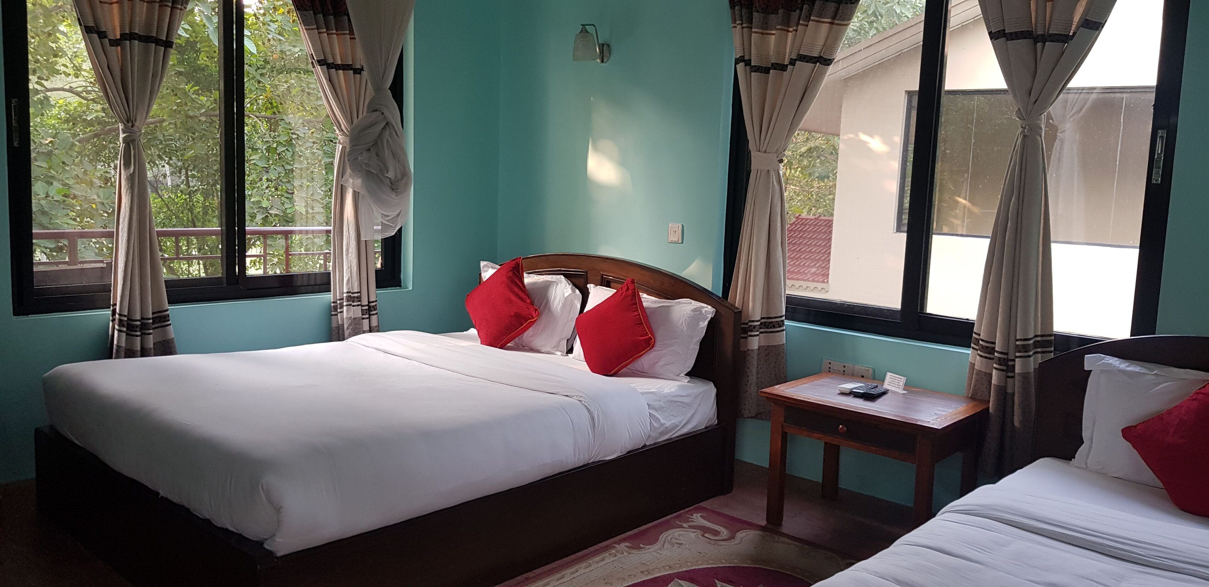 A bedroom with a bed, a nightstand, and a window with curtains.