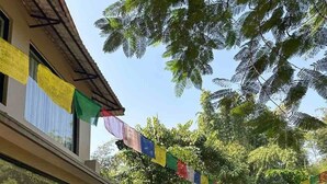 Un edificio con jardín, cerca de bambú y banderas de oración coloridas.