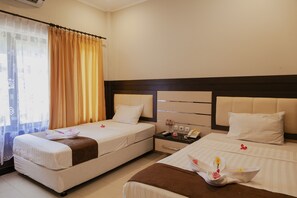 Een hotelkamer met twee bedden, een nachtkastje en een raam met gordijnen.