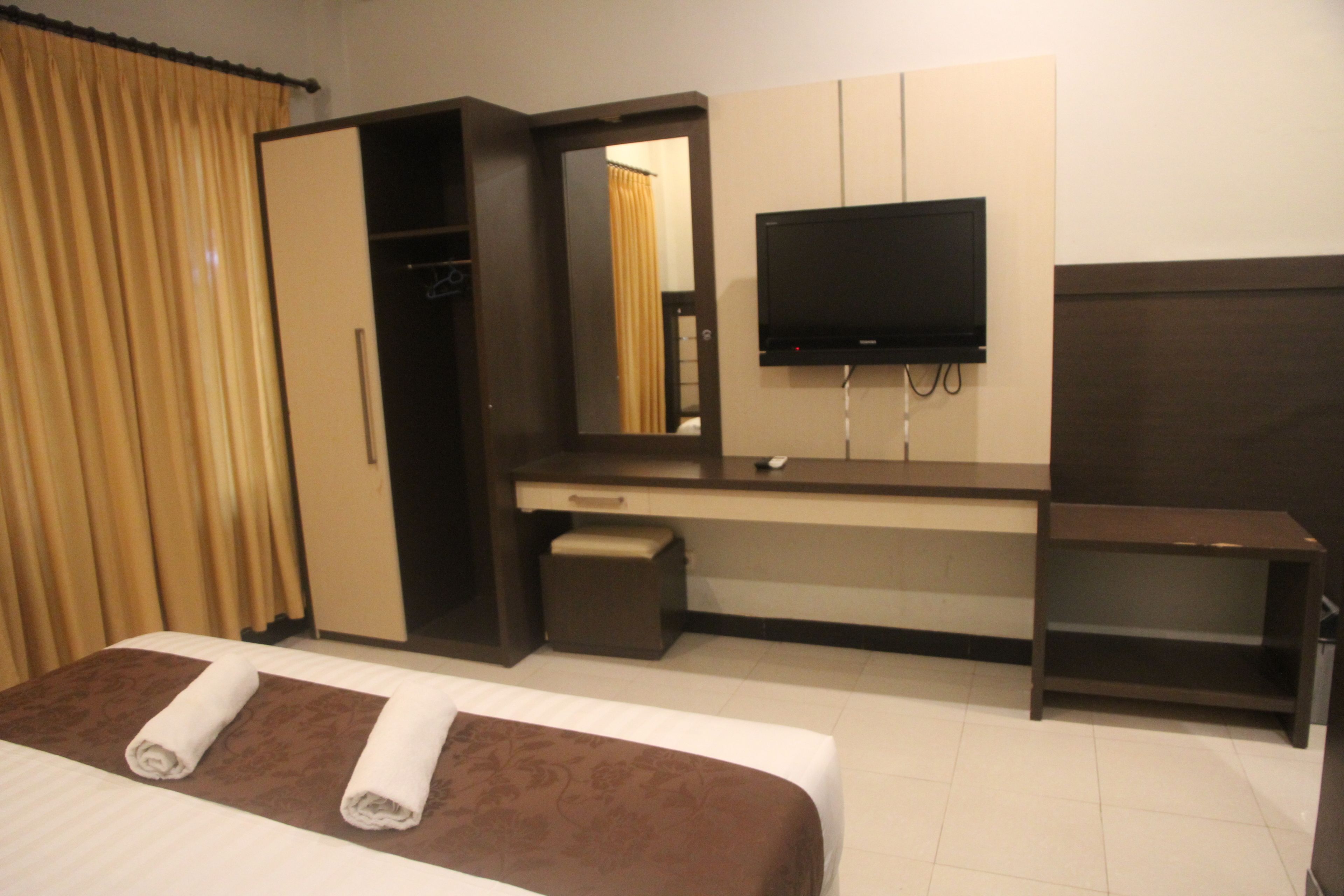 A hotel room with a bed, a desk, a television, and a wardrobe.