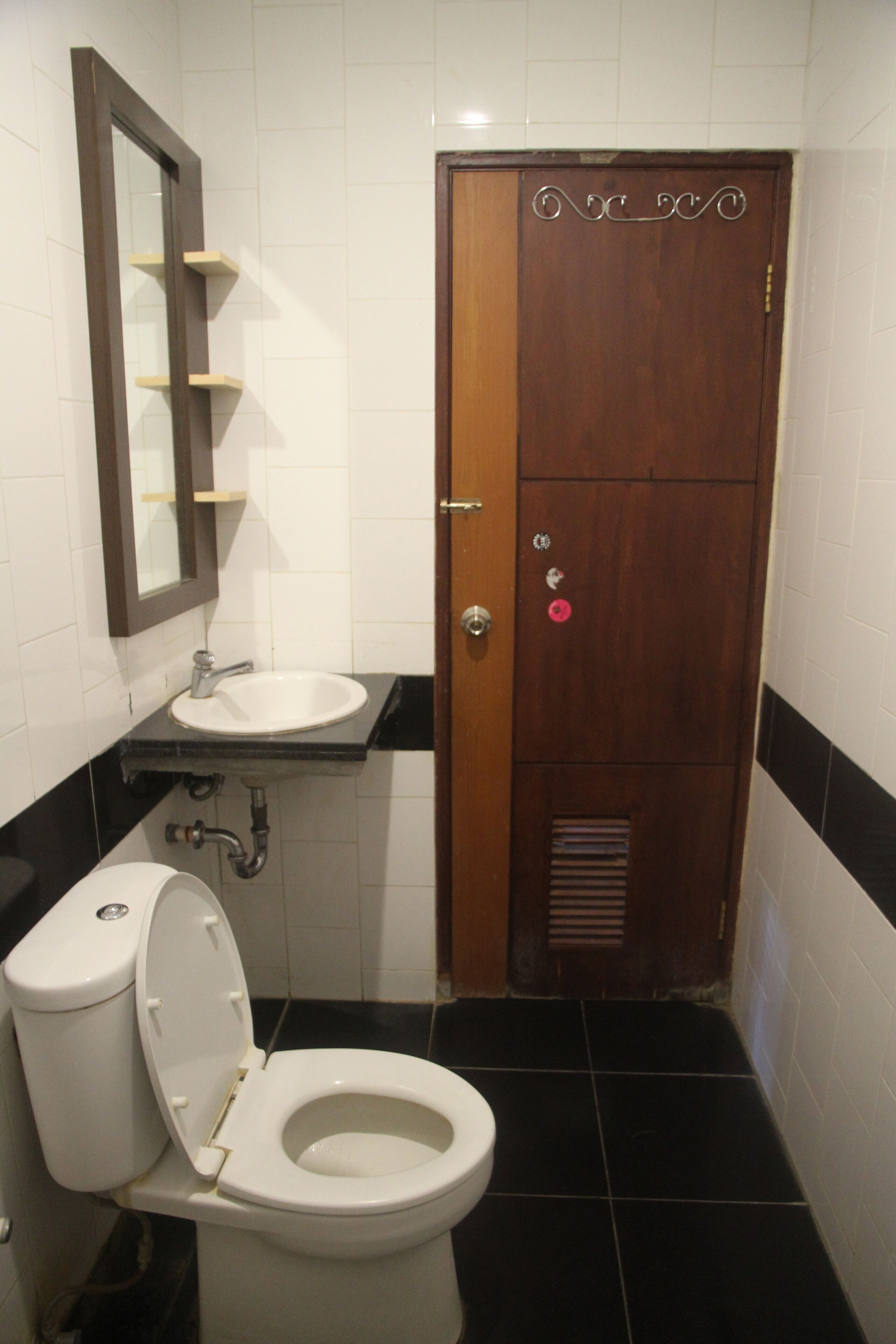 Un baño con inodoro blanco, lavamanos y espejo.