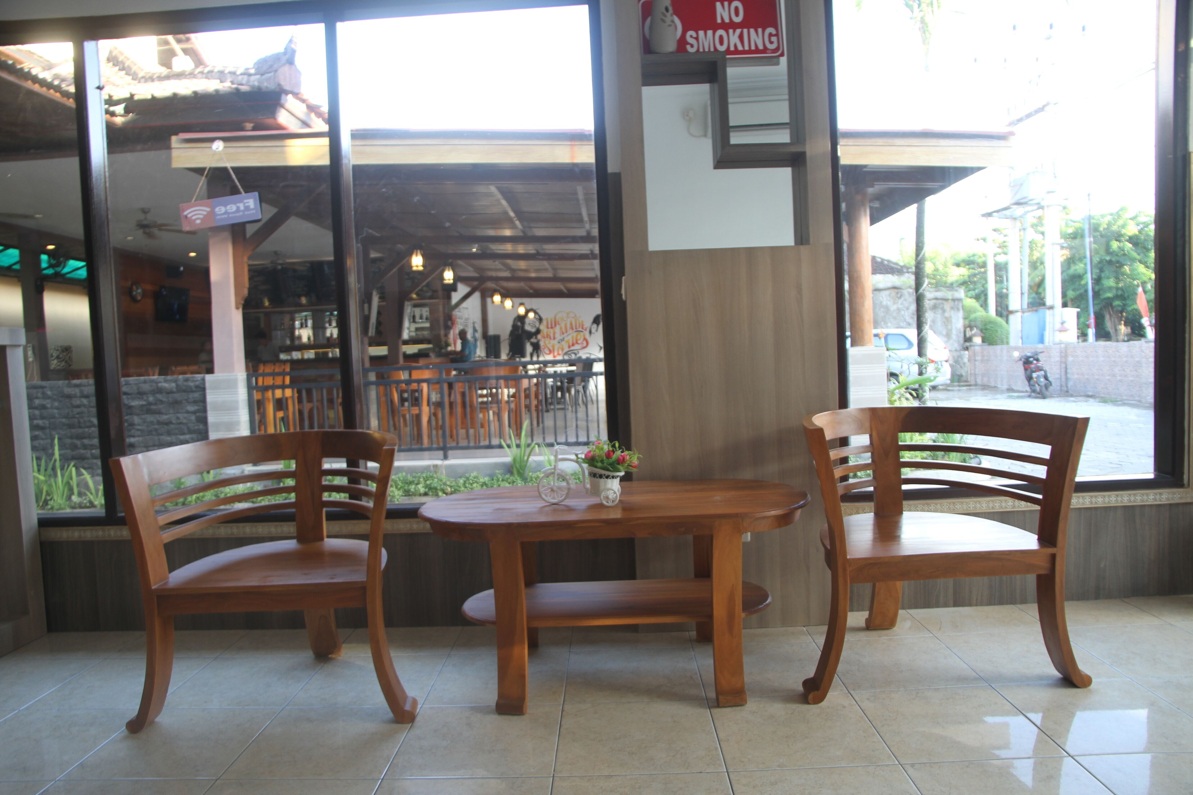 A restaurant interior with wooden chairs and a table, a 'No Smoking' sign, and a view of the street outside.