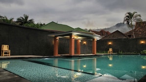 A swimming pool with a covered seating area and a view of a mountain. - Puri Senggigi Hotel (Senggigi)