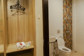Een badkamer met een houten wastafelmeubel, een handdoekrek, een toilet en een douchegedeelte.