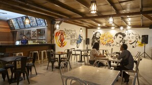 A restaurant with wooden ceiling beams, hanging pendant lights, and a bar area. Tables and chairs are arranged for dining. - Puri Senggigi Hotel (Senggigi)