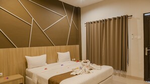 A modern hotel room with a large bed, a wooden headboard, and a curtain on the window. - Puri Senggigi Hotel (Senggigi)
