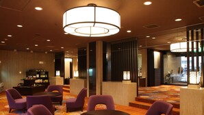Een hotel lobby met paarse stoelen, een ronde tafel en een grote kroonluchter.