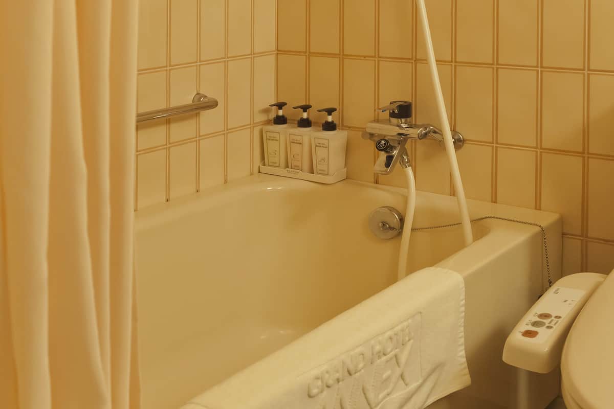 executive deluxe twin room | bathroom | combined shower/bathtub, free toiletries, hair dryer, slippers