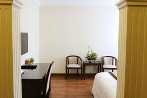 Habitació amb un llit, escriptori, dues cadires i taula petita amb una planta.