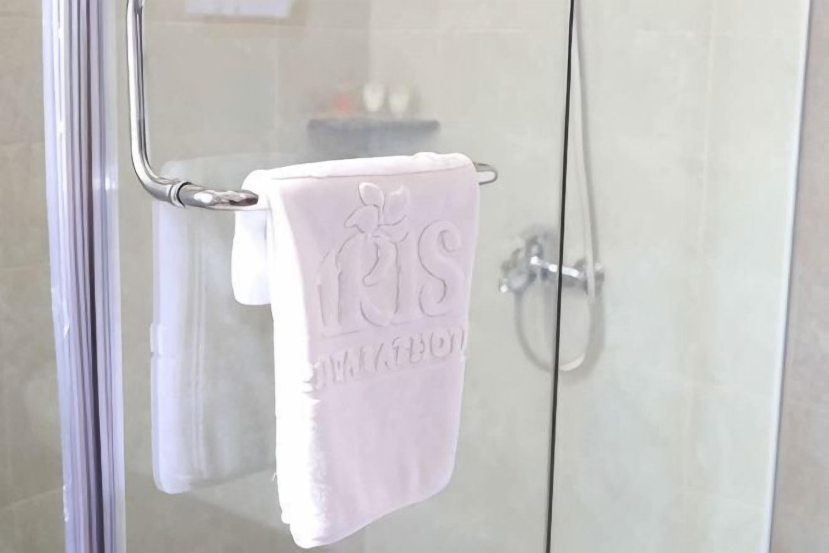 A glass shower enclosure with a metal towel rack holding a white towel.