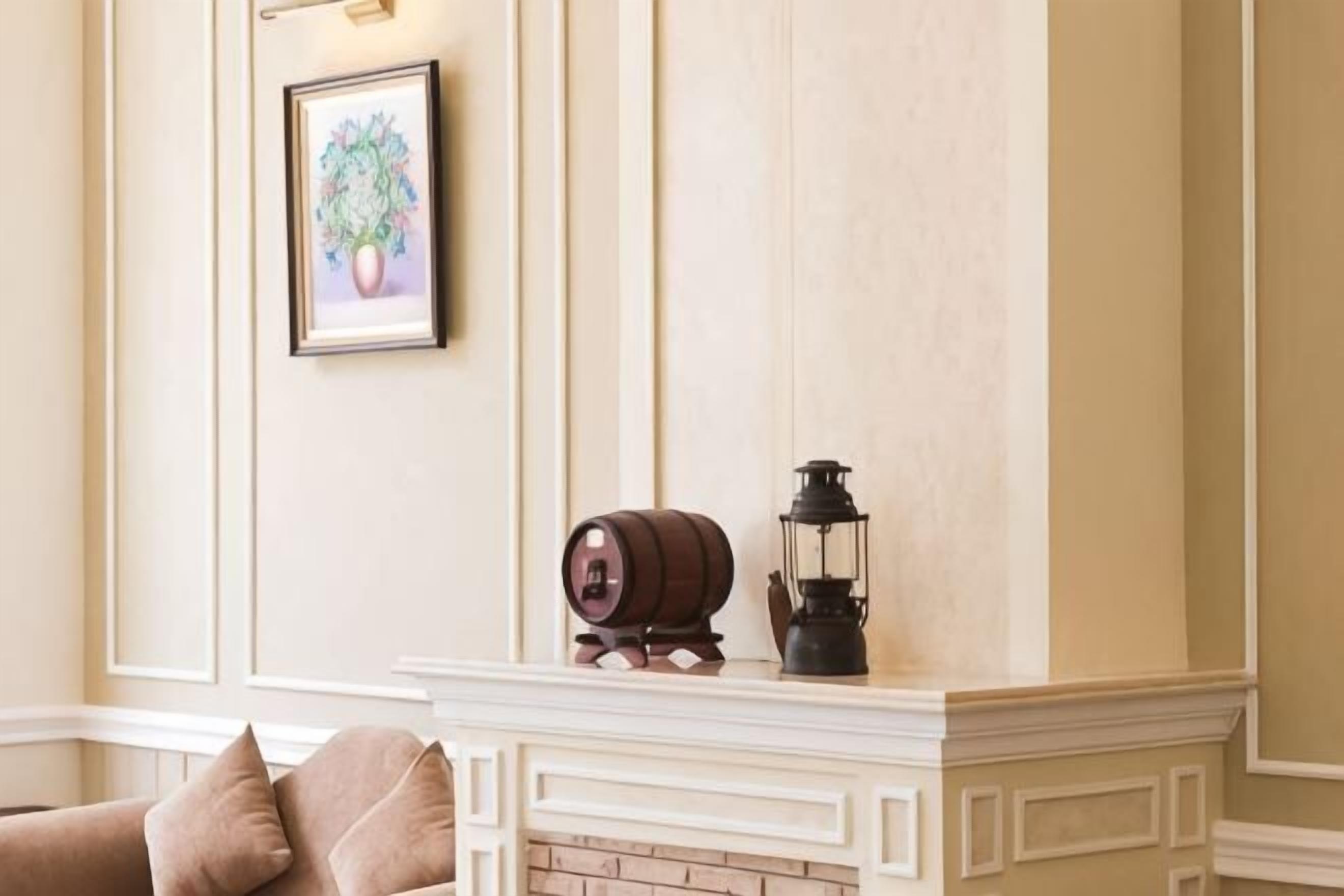 A fireplace with a mantel, a framed picture, and a lantern.