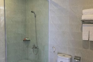 A shower with a glass door, a toilet, and a towel rack with towels.