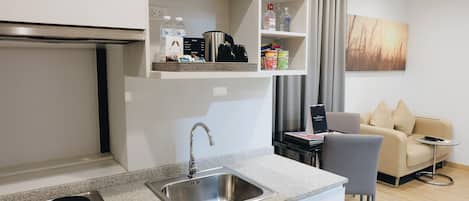 Una cocina moderna con estufa integrada, pileta de acero inoxidable y una encimera con cafetera y estantes de almacenamiento.