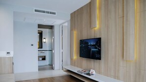 Una habitación de hotel moderna con un panel de pared de madera, un televisor montado y una consola blanca.