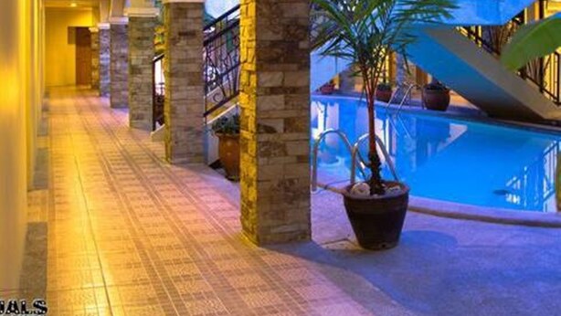 Un pasillo de hotel con zona de piscina, que incluye una escalera y plantas en macetas.