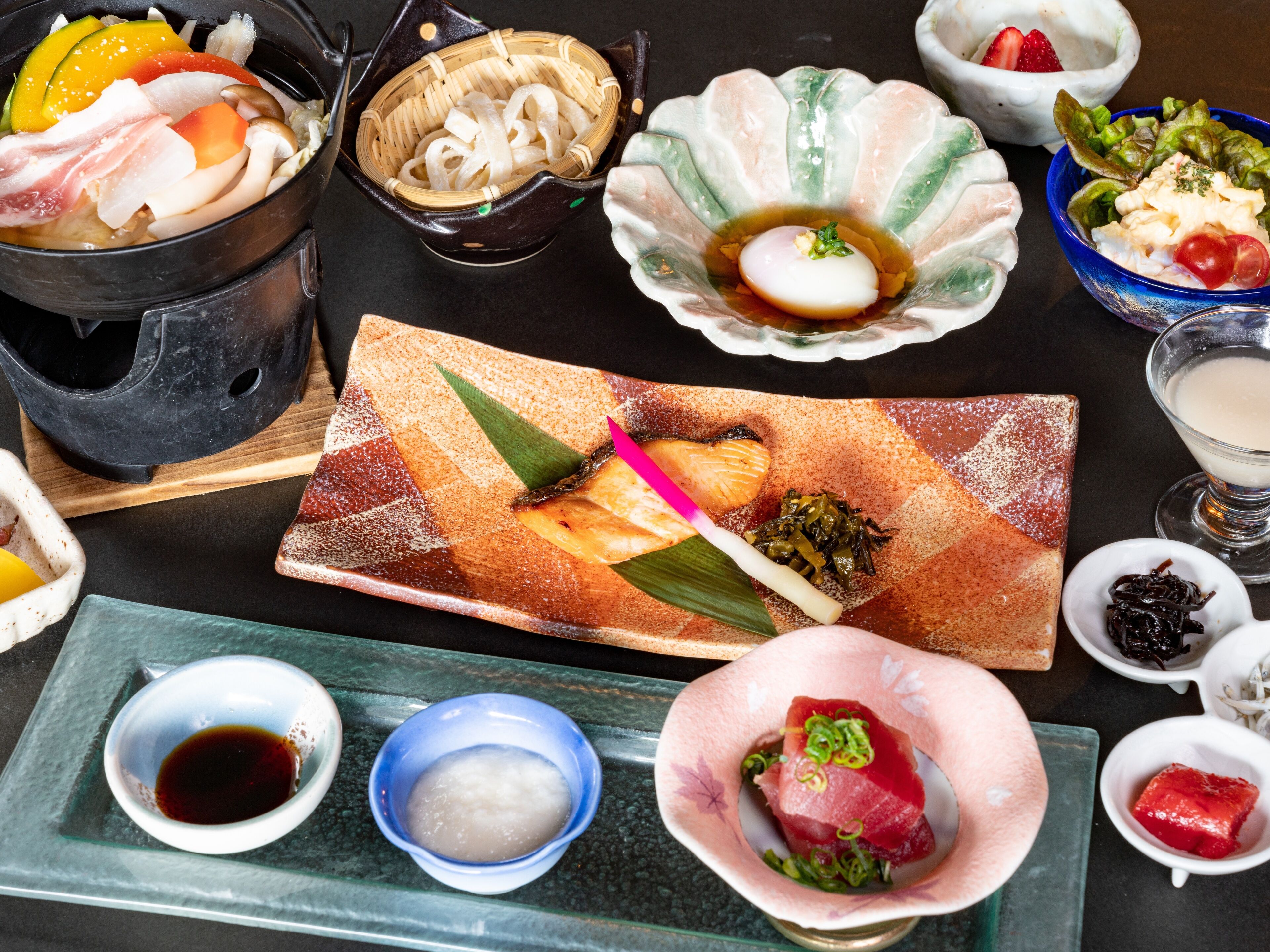 Un assortiment de plats comprenant du sashimi, des sushis et un bol de soupe.