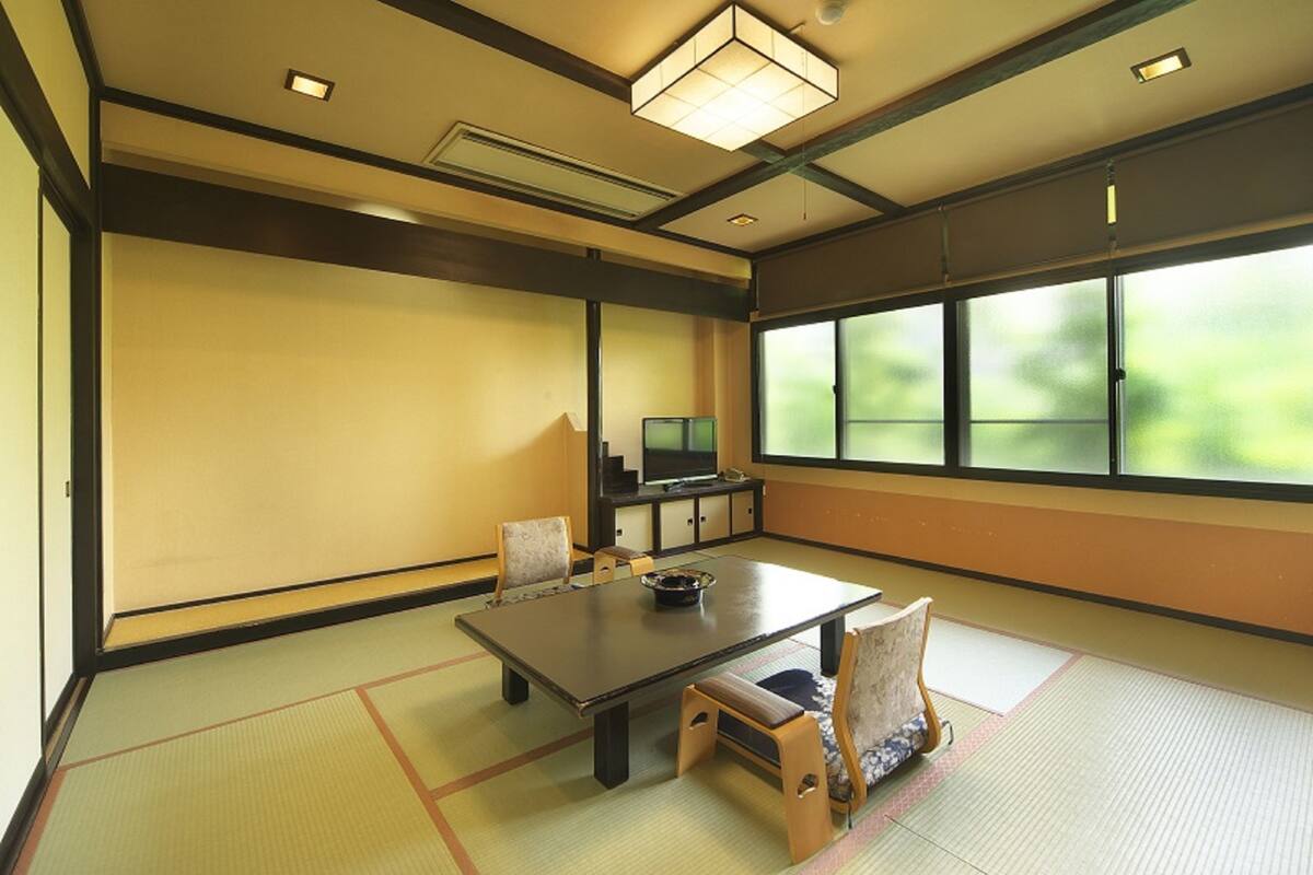 A traditional Japanese room with tatami flooring, a low table, and a television.