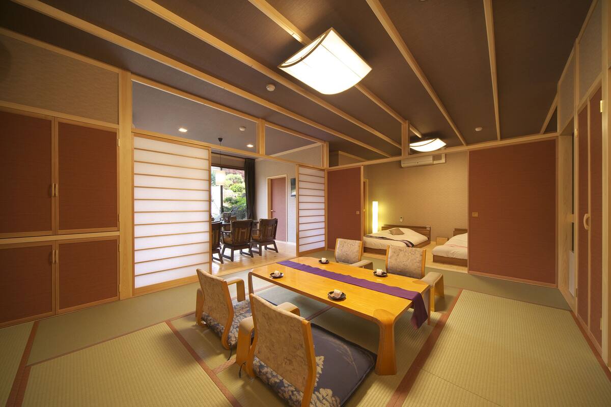 A traditional Japanese room with tatami flooring, a low table with cushions, and sliding doors.