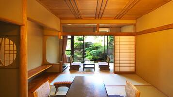 A traditional Japanese room with tatami flooring, a low table, and sliding doors leading to a garden.