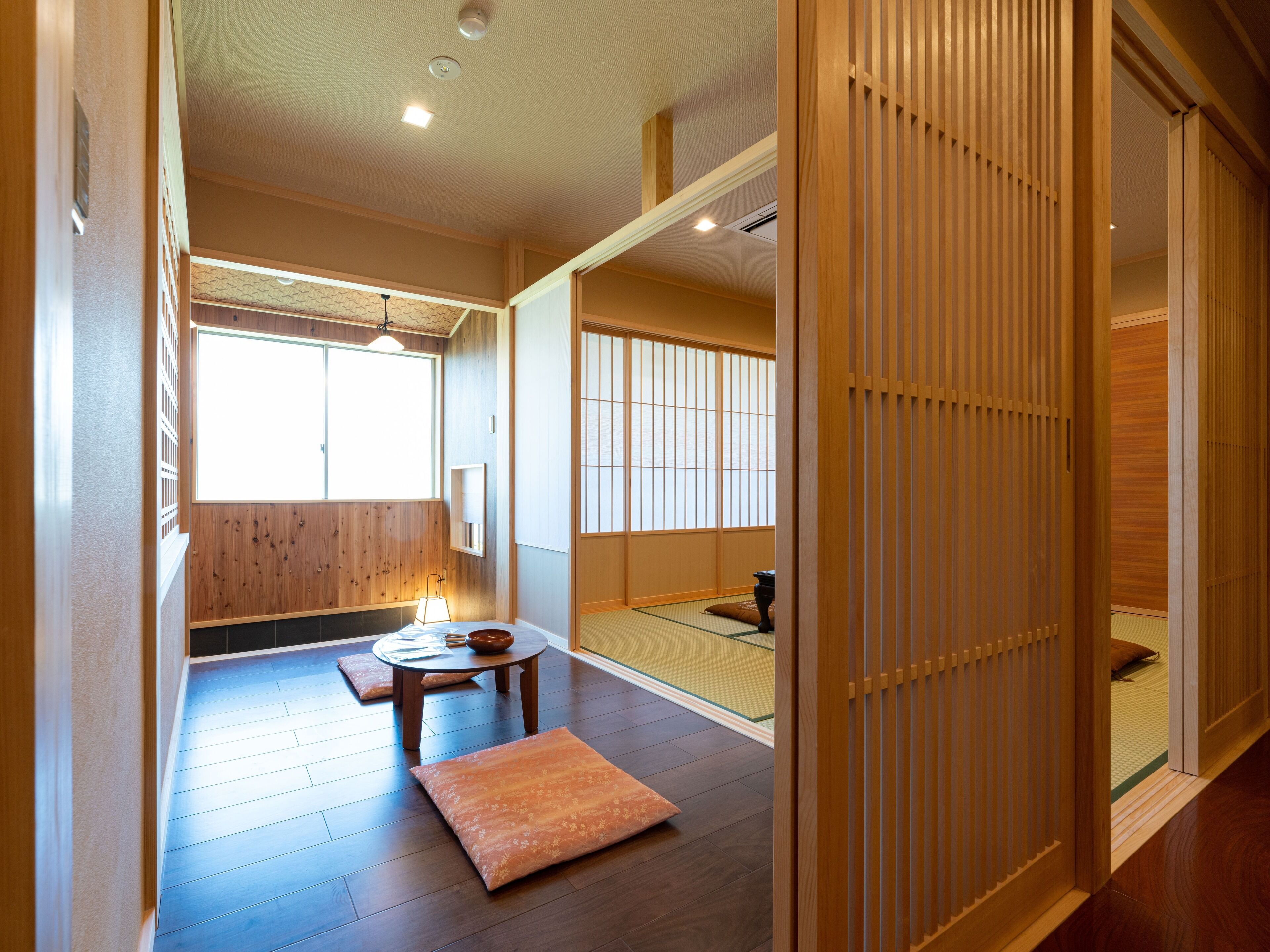 Una habitación japonesa tradicional con suelo de tatami, una mesa baja con cojines y puertas correderas.