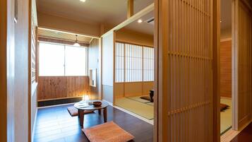 Una habitación japonesa tradicional con suelo de tatami, una mesa baja con cojines y puertas correderas.
