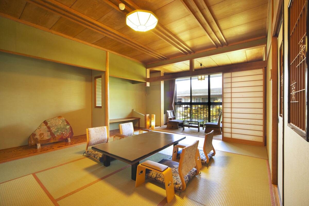 A traditional Japanese room with tatami flooring, a low table, and wooden furniture.