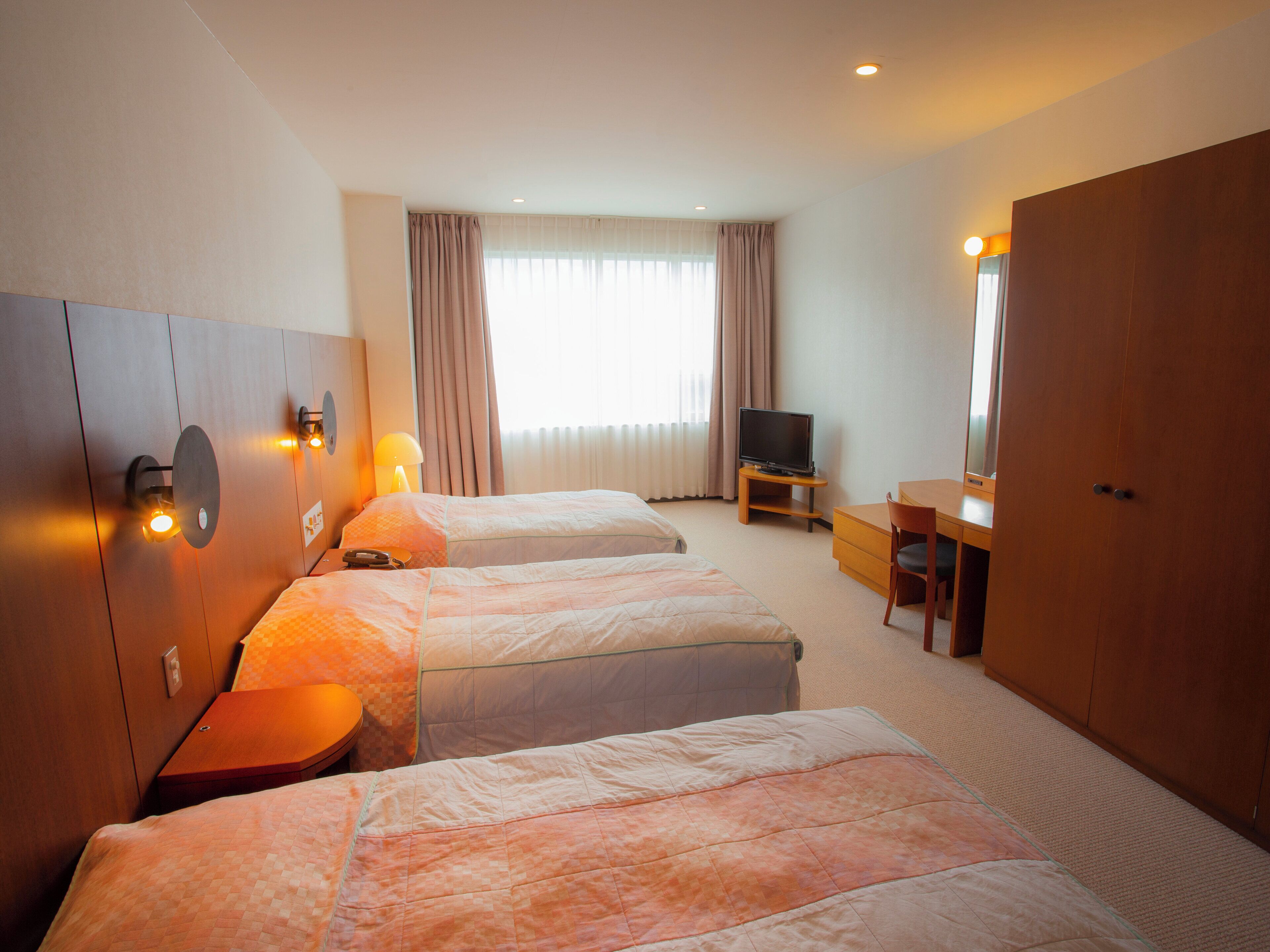 A hotel room with two beds, a television, a desk, and a wardrobe.
