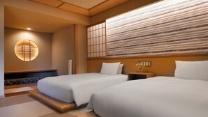 Habitación de hotel con dos camas, un tradicional panel japonés shoji y un aplique de pared.