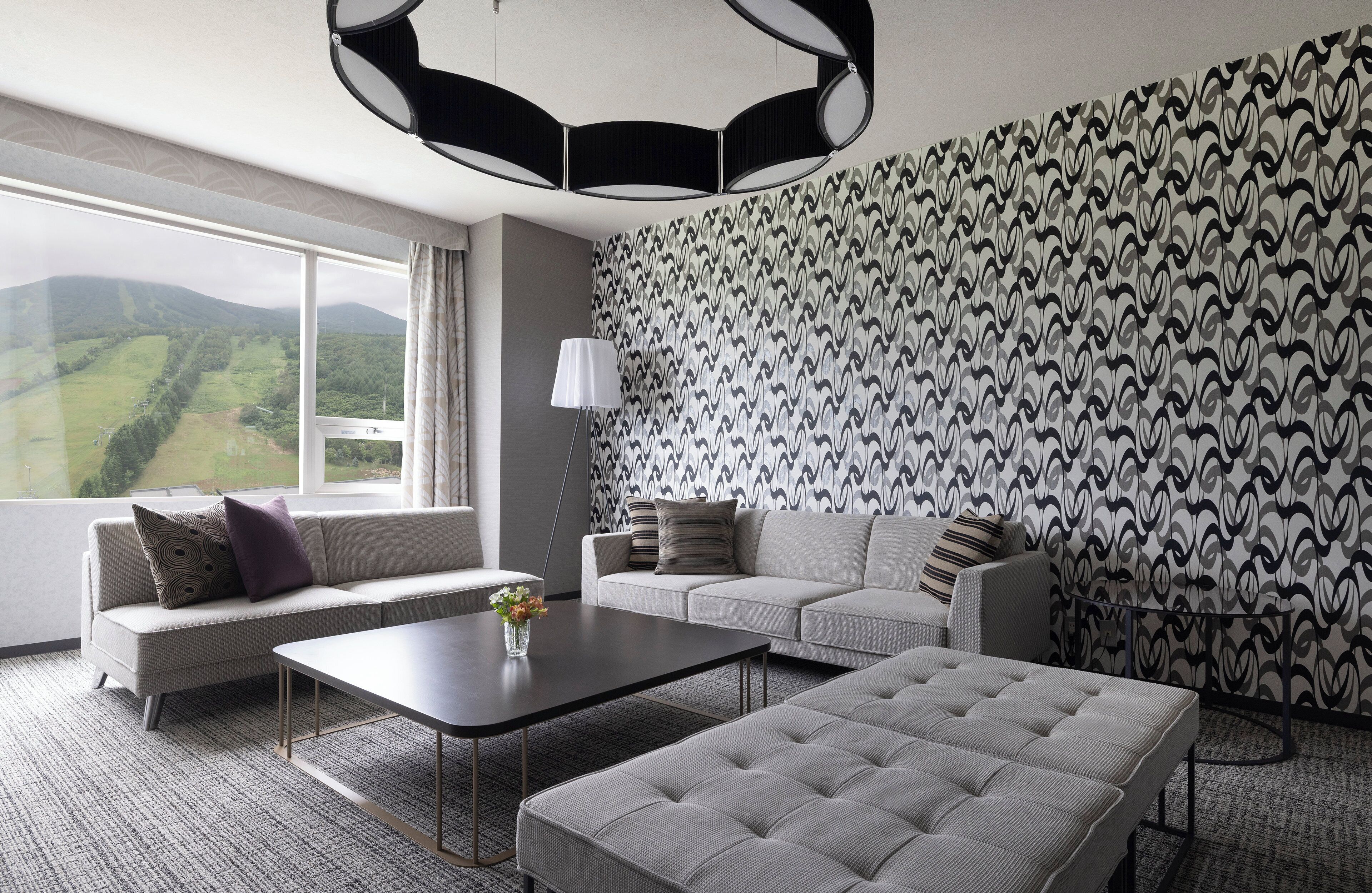 A modern living room with a sofa, a coffee table, and a patterned wall.