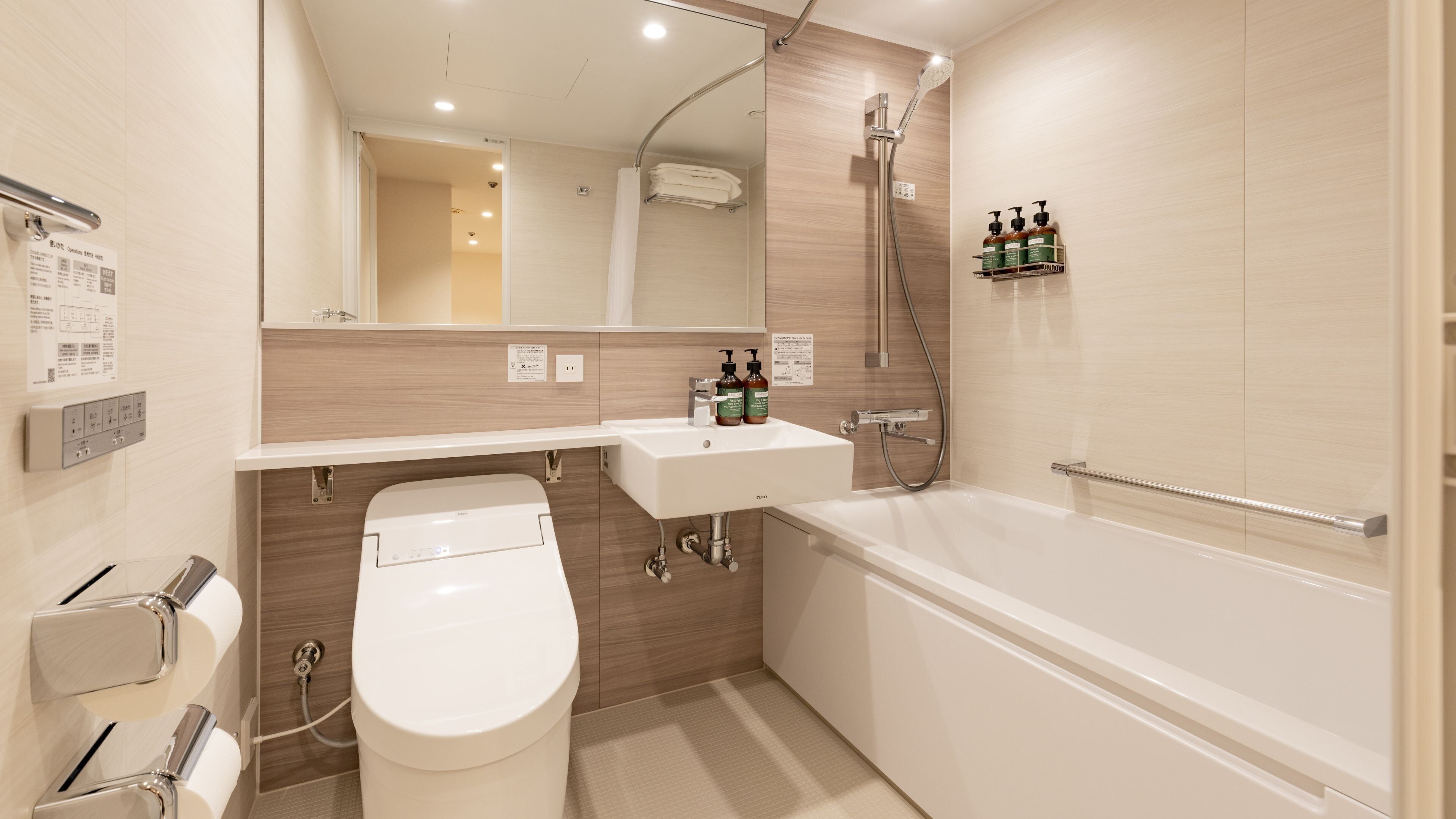 A modern bathroom with a toilet, sink, and bathtub. There is a showerhead and a shelf with toiletries.