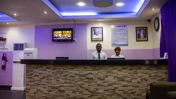 A reception area with a stone wall, a television mounted on the wall, and a suggestion box.