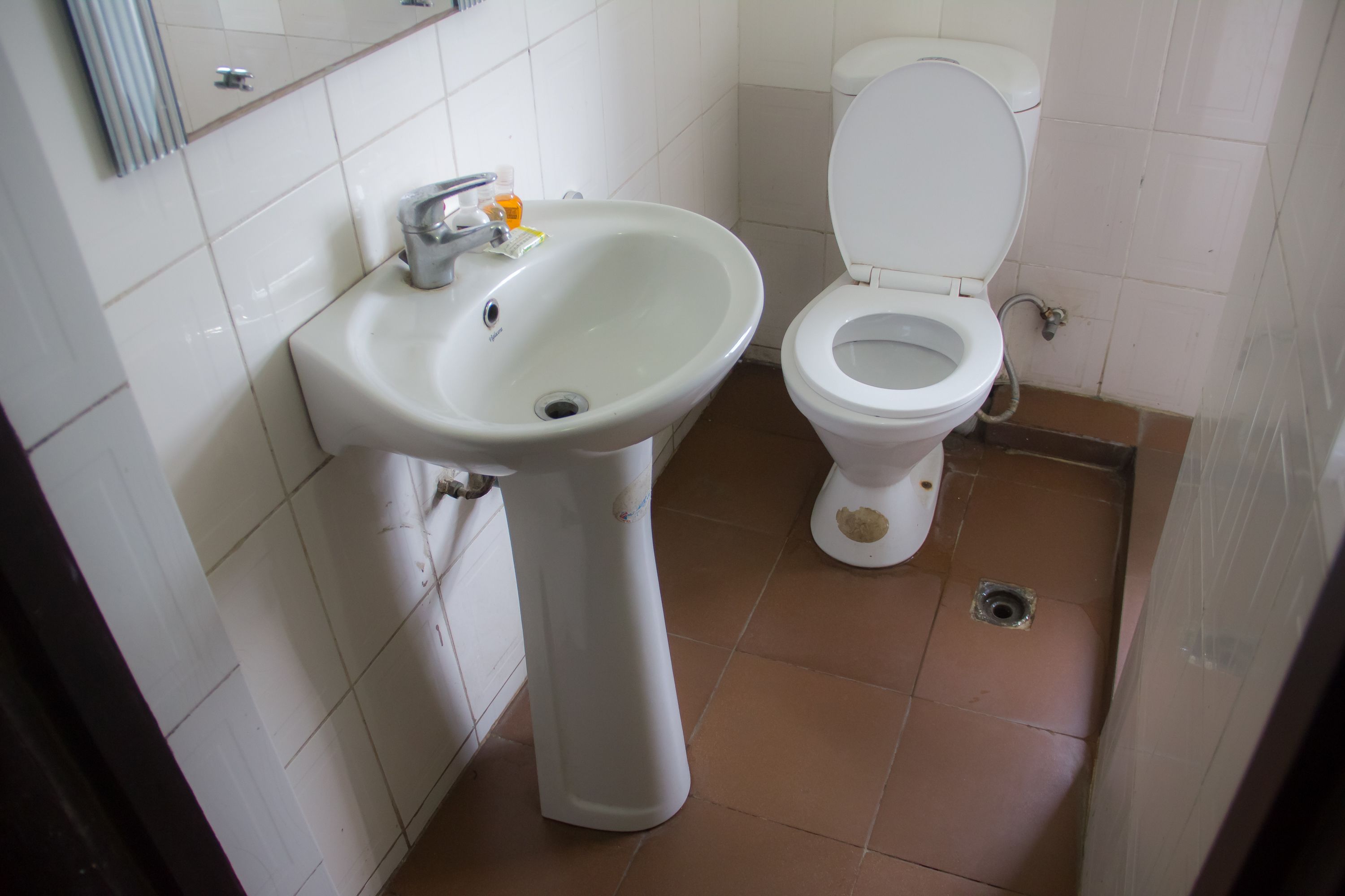 A bathroom with a white sink, toilet, and tiled floor.
