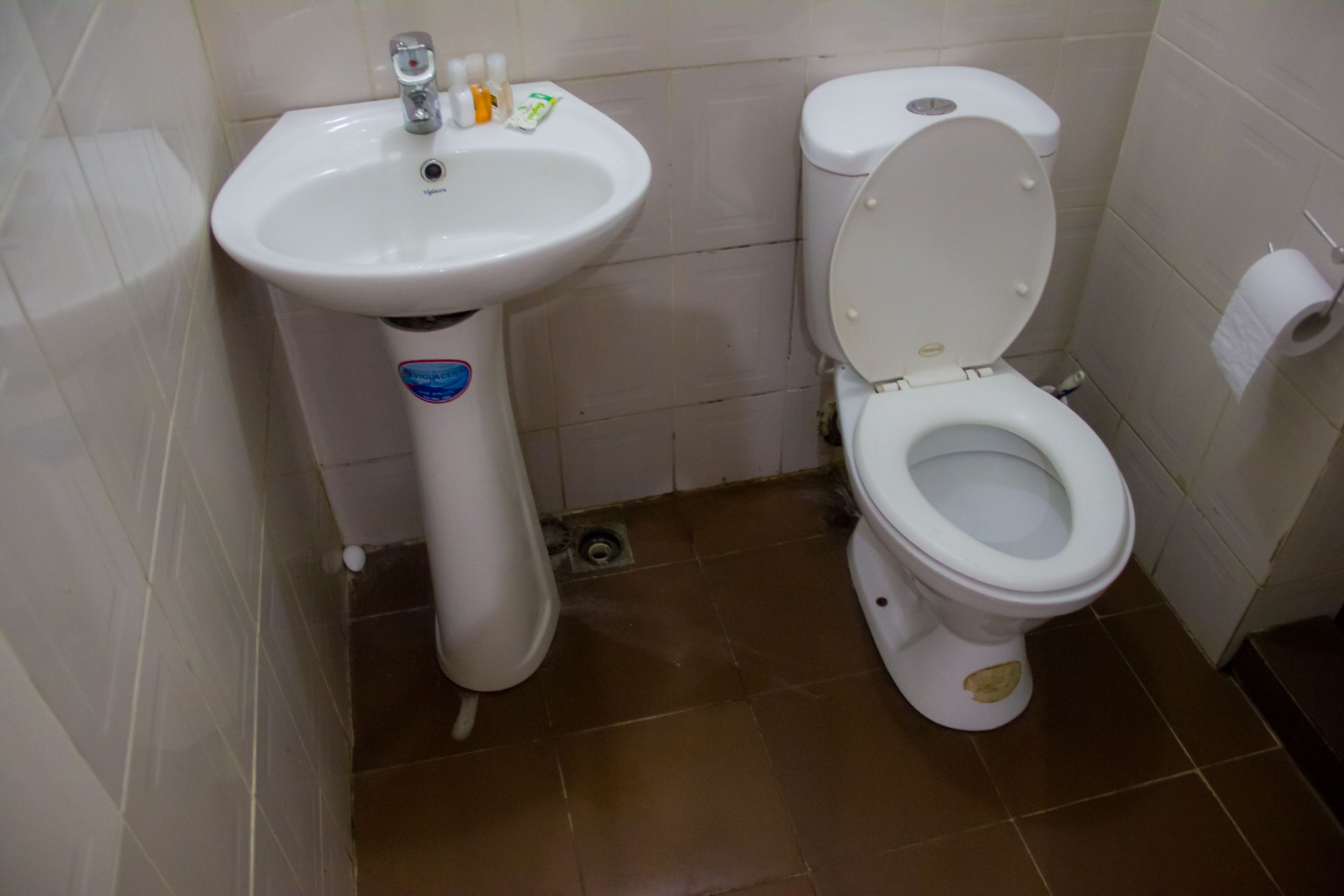 A bathroom with a white sink, toilet, and tiled floor.