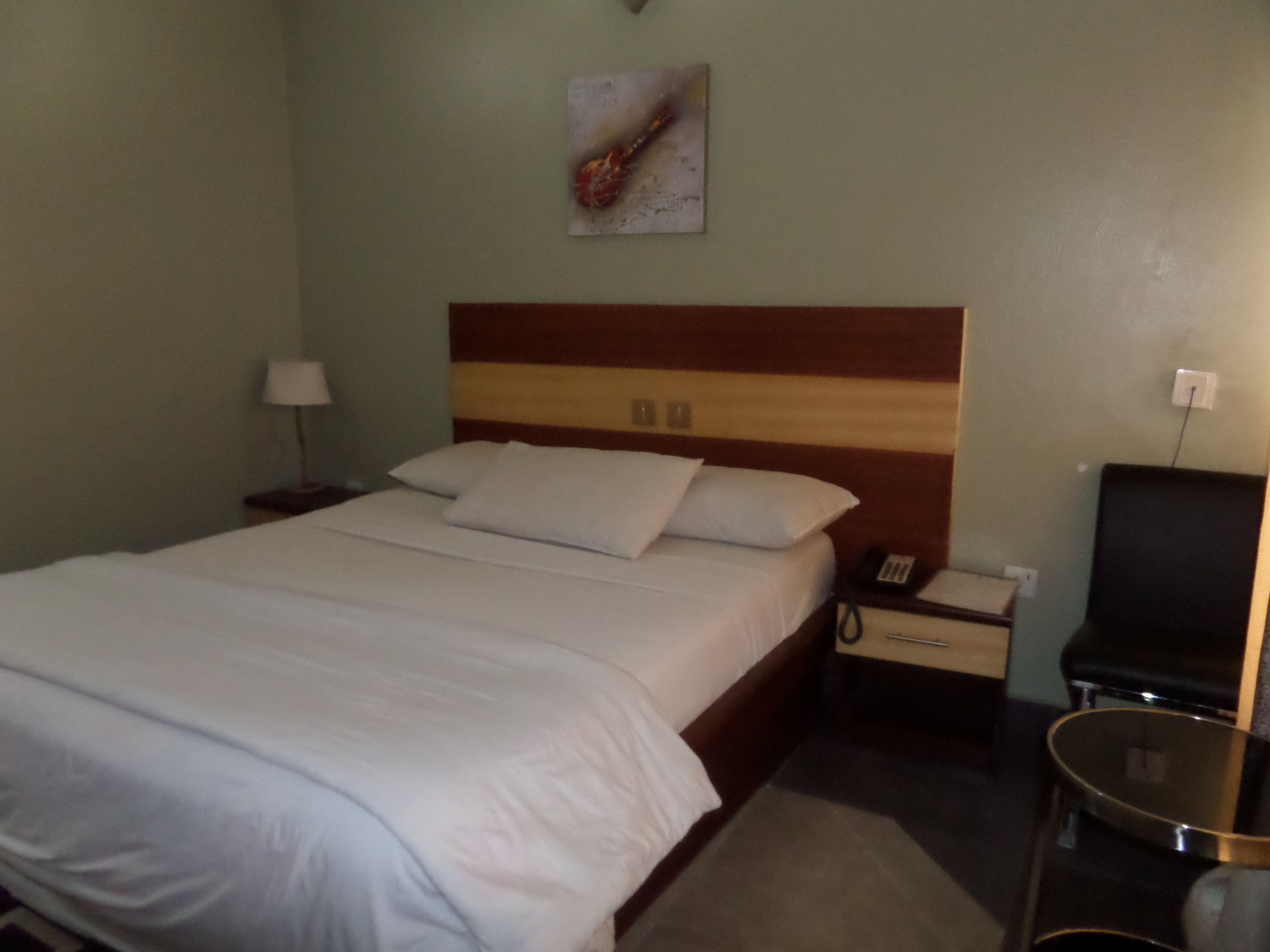 Ein Hotelzimmer mit Bett, Nachttisch, Lampe und einem kleinen Tisch.