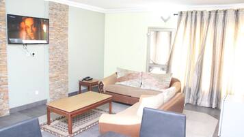 A living room with a sofa, coffee table, and TV mounted on a brick wall.