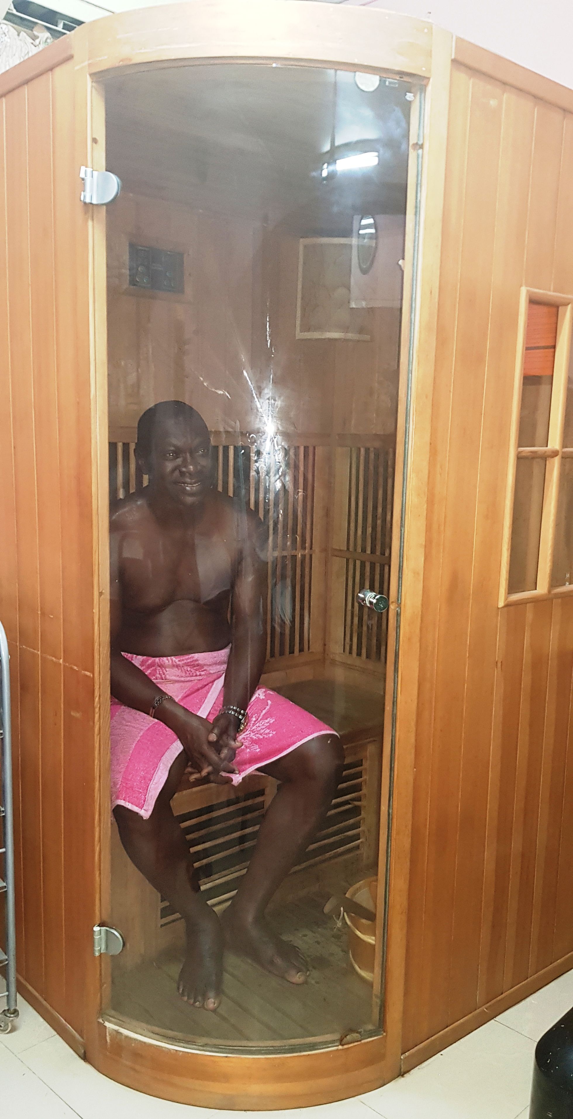 A sauna with a wooden exterior, a glass door, and a metal handle.