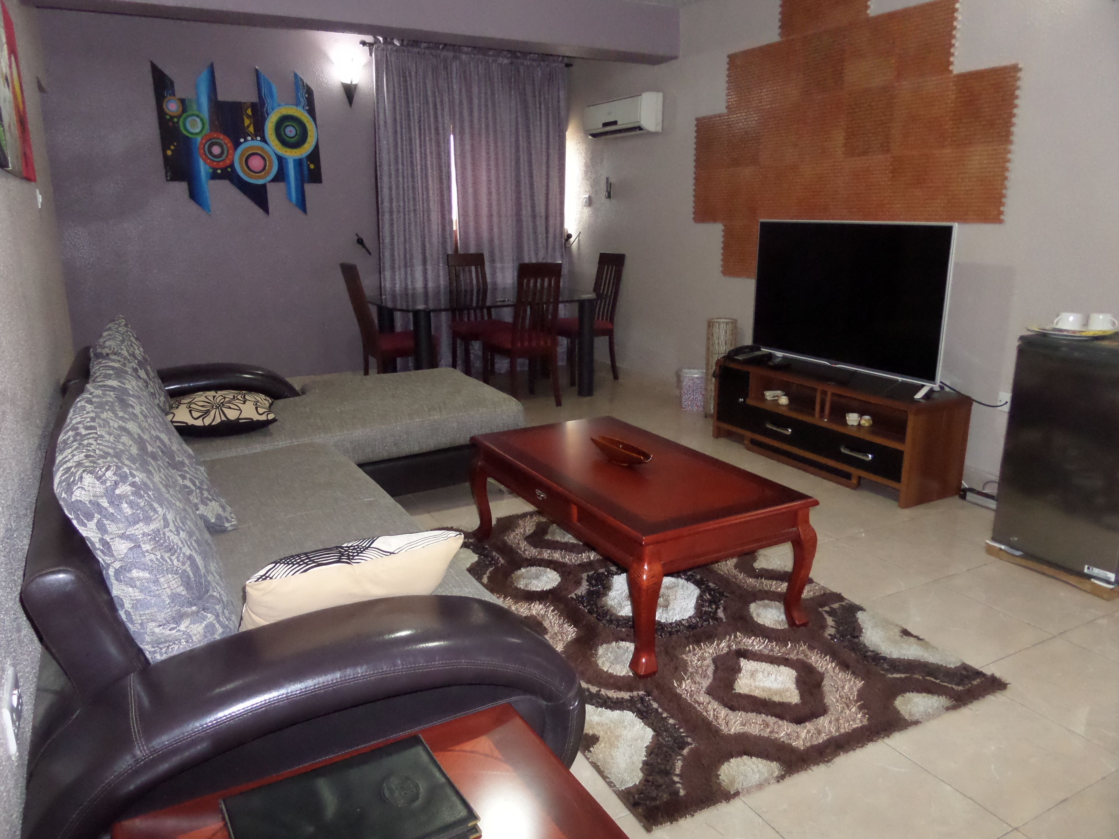 Una sala de estar con un sofá, una mesa de centro, un televisor y una alfombra estampada.