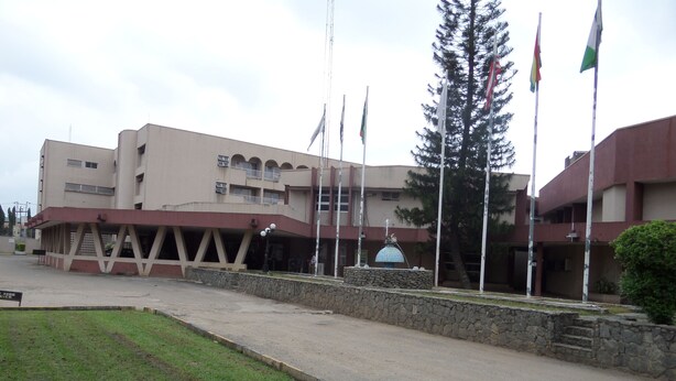 Un edificio de fachada de piedra, con varias banderas y una fuente en el centro.